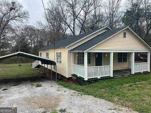 view of front of house with a carport, covered porch, and a front yard