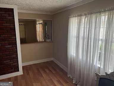 unfurnished room with plenty of natural light, dark wood-type flooring, and a textured ceiling