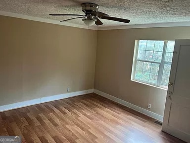 unfurnished room featuring ceiling fan, light hardwood / wood-style floors, and a textured ceiling