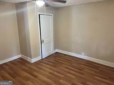 empty room with a textured ceiling, dark hardwood / wood-style flooring, and ceiling fan