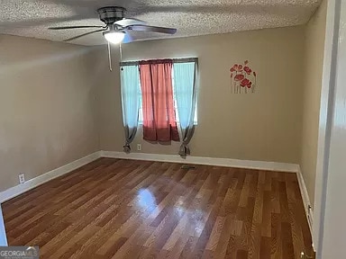 empty room featuring ceiling fan, dark hardwood / wood-style floors, and a textured ceiling