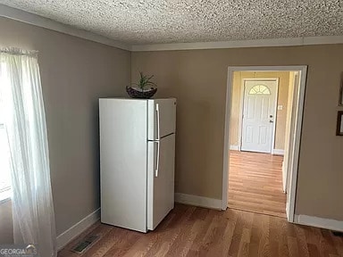 kitchen featuring white refrigerator, light hardwood / wood-style floors, a textured ceiling, and plenty of natural light