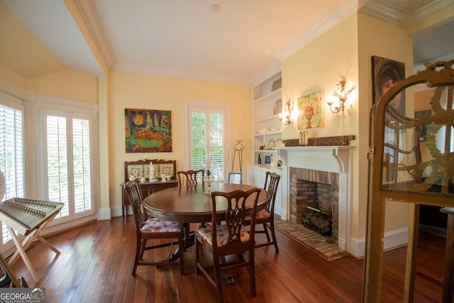 dining space featuring dark wood-type flooring, ornamental molding, a fireplace, and built in shelves