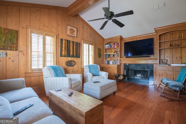 living room with hardwood / wood-style flooring, wooden walls, lofted ceiling with beams, built in shelves, and ceiling fan