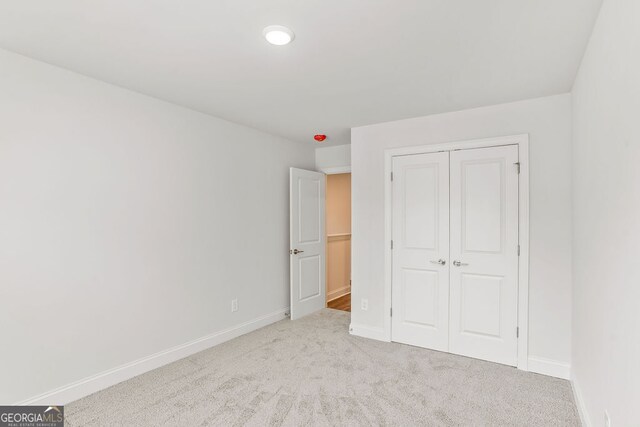 unfurnished bedroom with a closet and light colored carpet