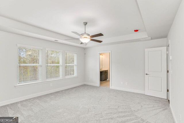 unfurnished bedroom with connected bathroom, light colored carpet, and ceiling fan