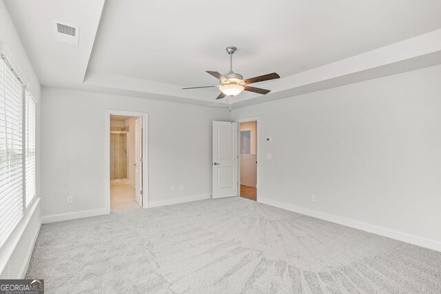 spare room featuring a tray ceiling, ceiling fan, and light colored carpet