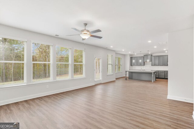 unfurnished living room featuring ceiling fan, sink, and light hardwood / wood-style floors