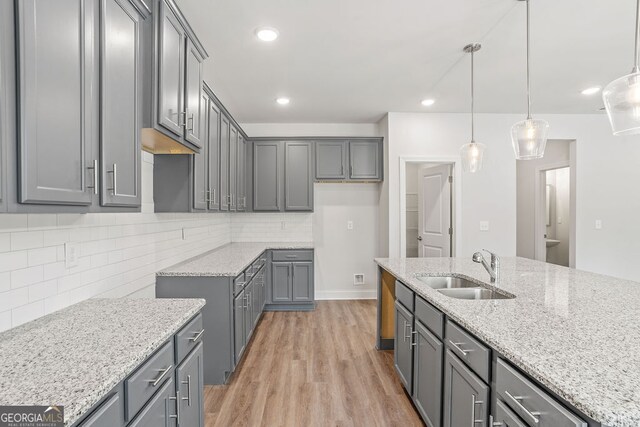 kitchen with sink, light hardwood / wood-style flooring, pendant lighting, gray cabinets, and decorative backsplash