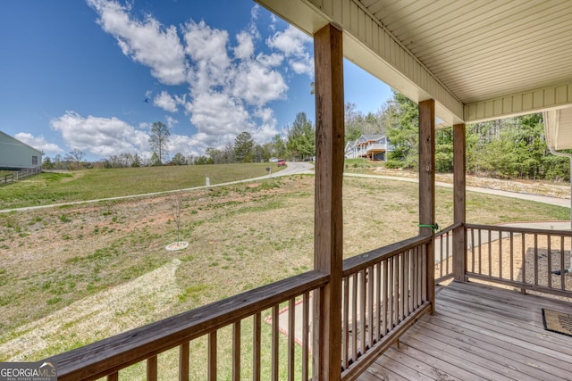 wooden deck with covered porch and a rural view