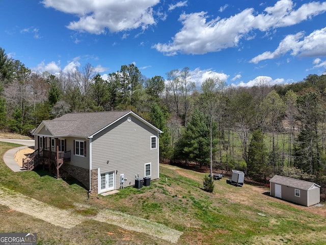 view of side of property featuring a lawn and a storage unit