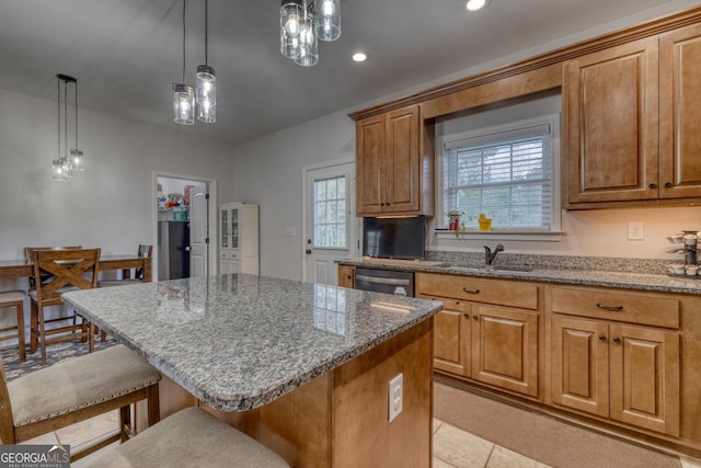 kitchen with a center island, dishwasher, sink, decorative light fixtures, and a breakfast bar