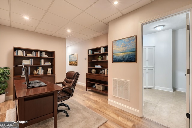 office featuring light wood-type flooring and a drop ceiling