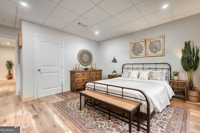 bedroom with a paneled ceiling and light wood-type flooring