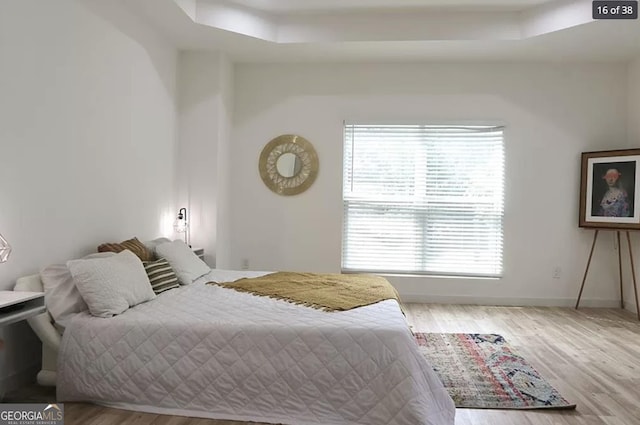 bedroom featuring light hardwood / wood-style floors and a raised ceiling