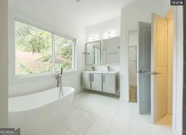 bathroom with a tub to relax in, tile patterned floors, and vanity