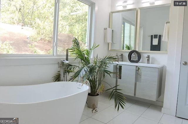 bathroom with tile patterned floors, plenty of natural light, vanity, and a bath