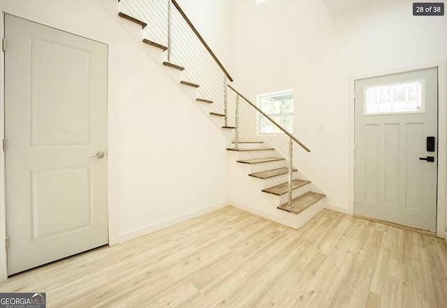 entryway with a towering ceiling and light hardwood / wood-style flooring