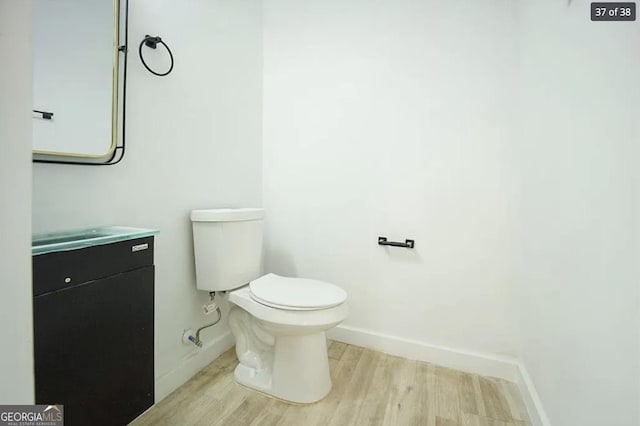 bathroom with toilet, vanity, and hardwood / wood-style flooring