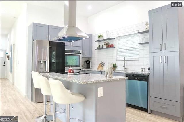 kitchen with a center island, decorative backsplash, a kitchen bar, island exhaust hood, and stainless steel appliances