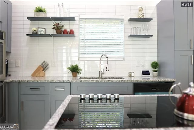 kitchen with gray cabinetry, light stone countertops, and sink