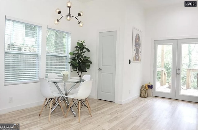 dining space with french doors, a chandelier, and light wood-type flooring