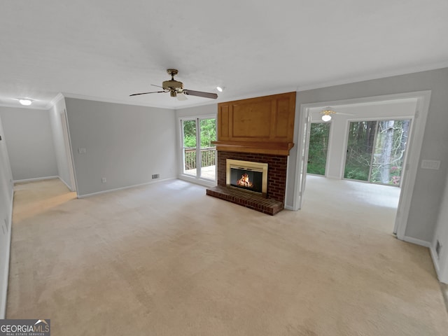 unfurnished living room featuring crown molding, light carpet, ceiling fan, and a fireplace