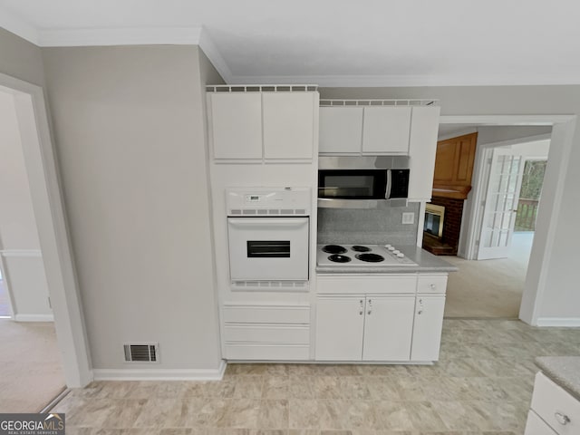 kitchen with white appliances, tasteful backsplash, light tile floors, and white cabinetry