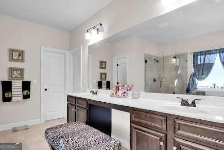 bathroom featuring tile flooring, walk in shower, and dual bowl vanity