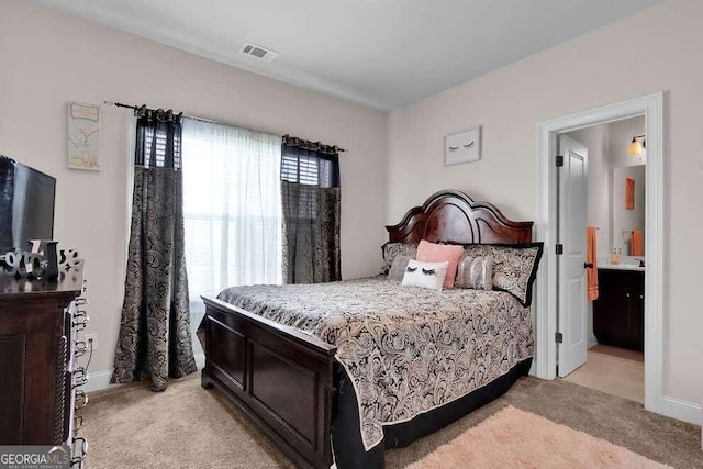 bedroom featuring multiple windows, light carpet, and ensuite bathroom