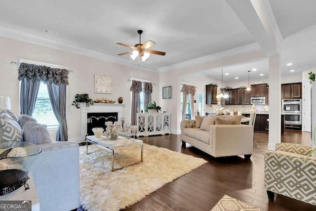 living room with ceiling fan, crown molding, and dark wood-type flooring