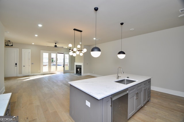 kitchen featuring a kitchen island with sink, dishwasher, decorative light fixtures, and sink