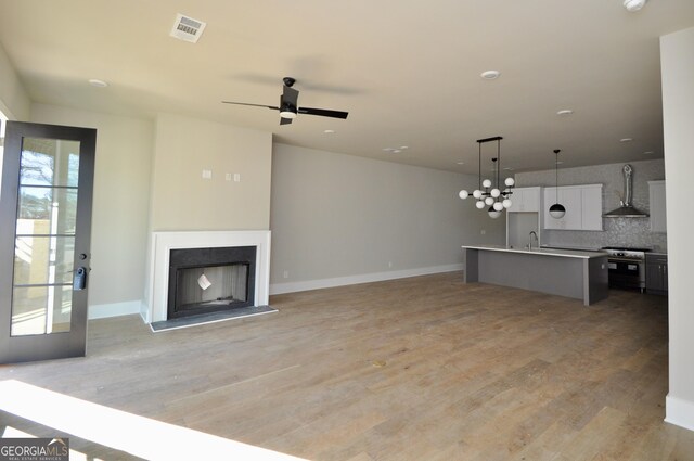 unfurnished living room with ceiling fan, light hardwood / wood-style floors, and sink