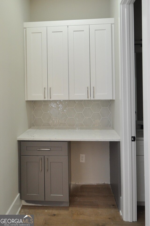 interior space with tasteful backsplash, white cabinetry, dark wood-type flooring, and built in desk