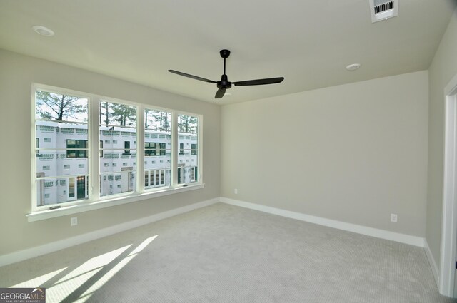 empty room with a healthy amount of sunlight, ceiling fan, and light carpet