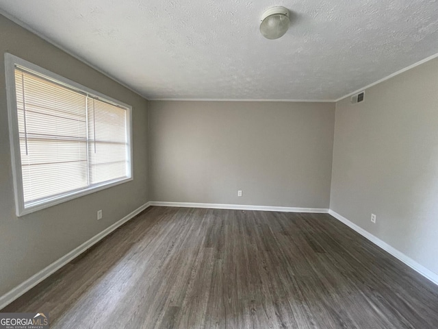 empty room with visible vents, dark wood finished floors, a textured ceiling, and baseboards