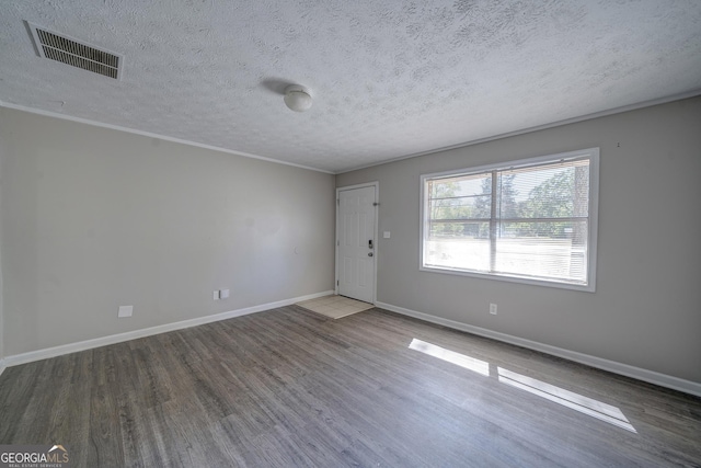 unfurnished room featuring a textured ceiling, dark wood-style flooring, visible vents, and baseboards