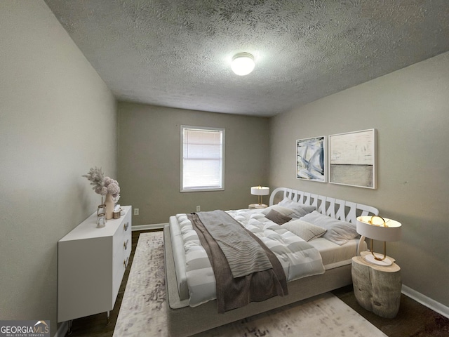 bedroom with a textured ceiling, dark wood finished floors, and baseboards