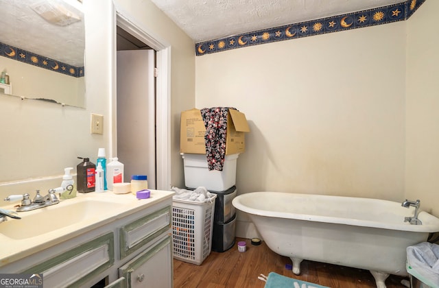 bathroom featuring a tub, hardwood / wood-style flooring, large vanity, and a textured ceiling