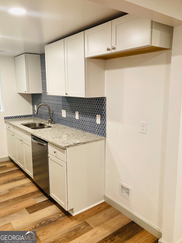 kitchen featuring white cabinets, sink, light wood-type flooring, stainless steel dishwasher, and light stone countertops