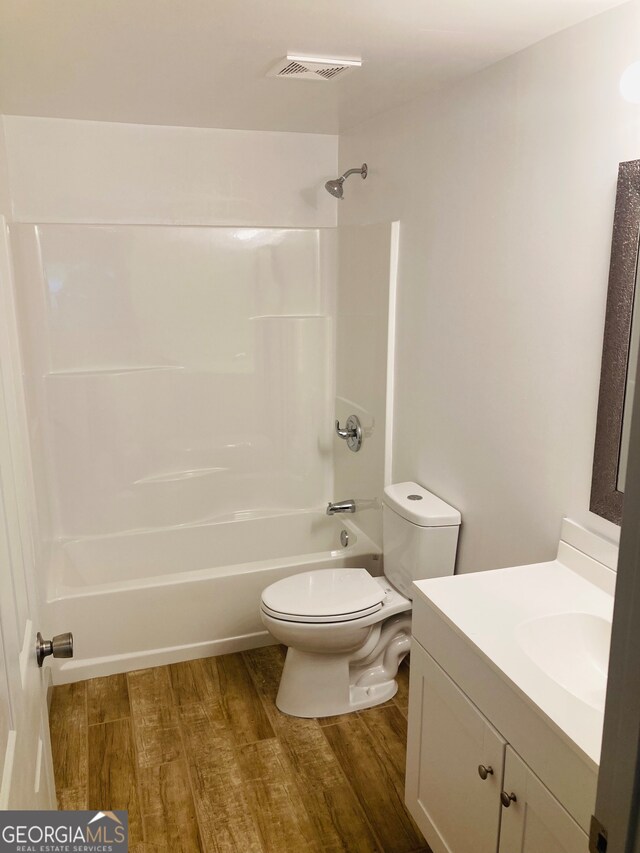 full bathroom with vanity with extensive cabinet space, toilet, bathtub / shower combination, and hardwood / wood-style floors