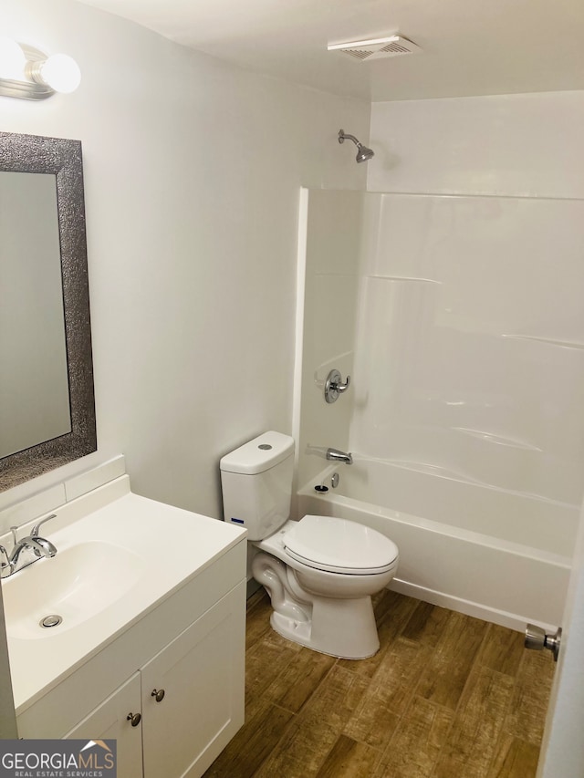 full bathroom with hardwood / wood-style floors, toilet, vanity with extensive cabinet space, and shower / washtub combination