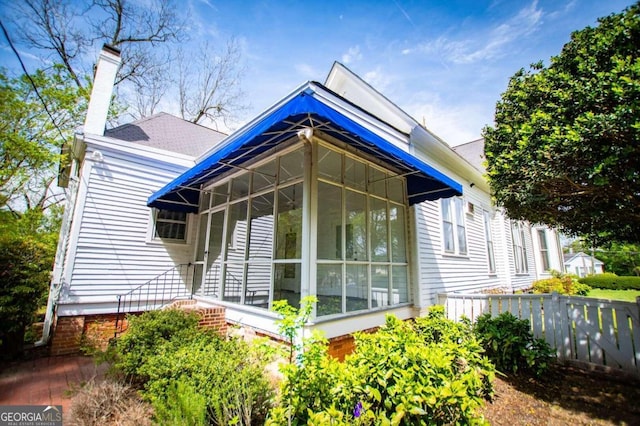 315 Dixie St, Carrollton, GA 30117 - view of home's exterior with fence, a sunroom, and a chimney