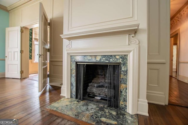 room details with ornamental molding, hardwood / wood-style floors, and a high end fireplace