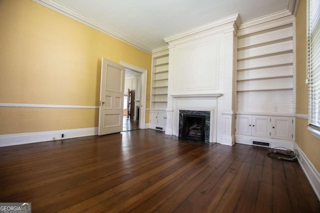 unfurnished living room with a premium fireplace, crown molding, dark hardwood / wood-style floors, and built in shelves