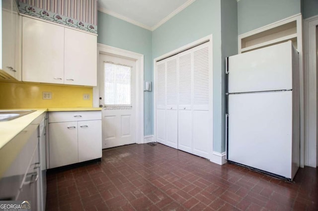 315 Dixie St, Carrollton, GA 30117 - kitchen featuring brick patterned floor, ornamental molding, light countertops, freestanding refrigerator, and white cabinetry