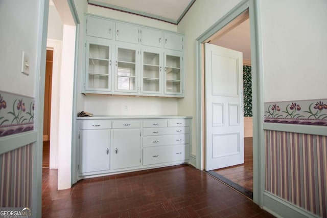 bar with dark hardwood / wood-style flooring, white cabinetry, and crown molding