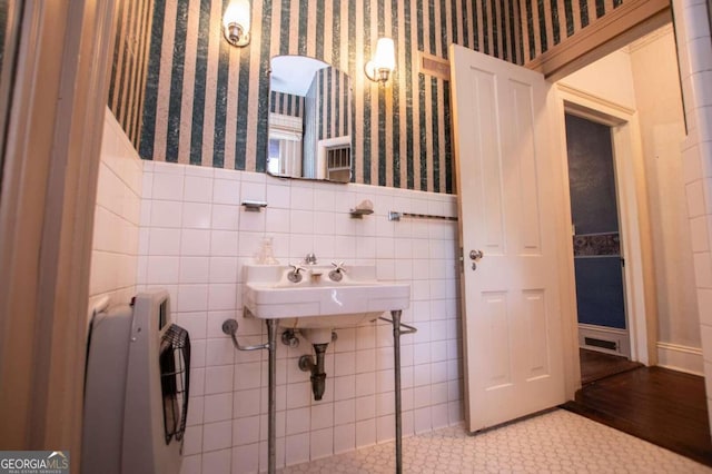 bathroom with radiator heating unit, sink, tile walls, and hardwood / wood-style flooring