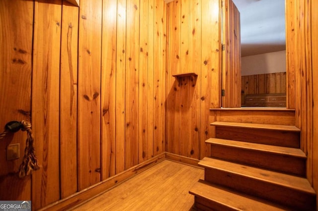 stairway featuring light hardwood / wood-style flooring and wooden walls