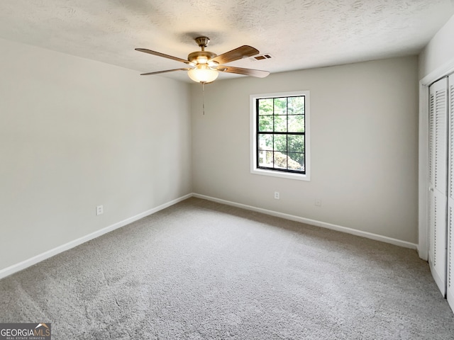 spare room featuring a textured ceiling, carpet floors, and ceiling fan